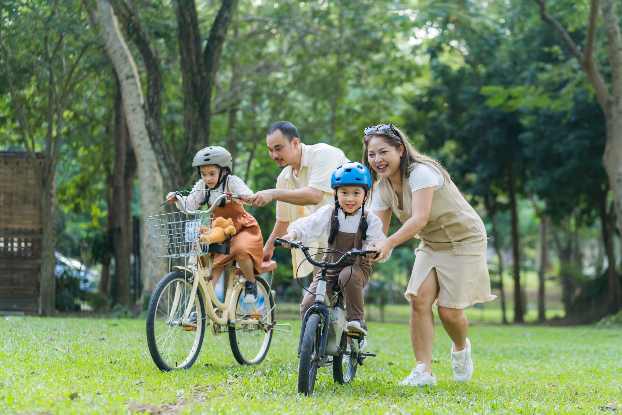young parents pushing their kids on bikes